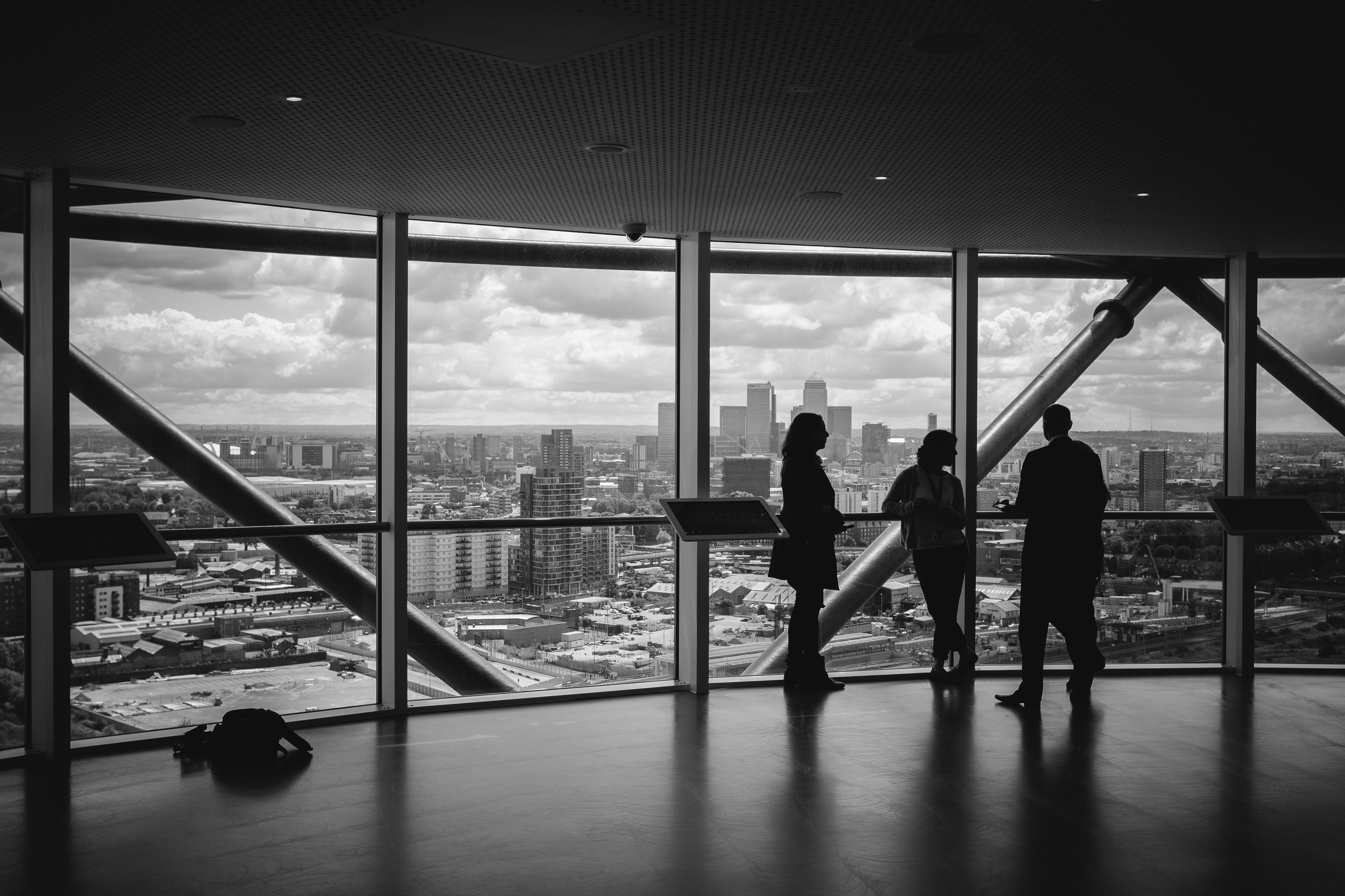 Trois dirigeants en silhouette devant les baies vitrées d'une tour, surplombant une skyline urbaine